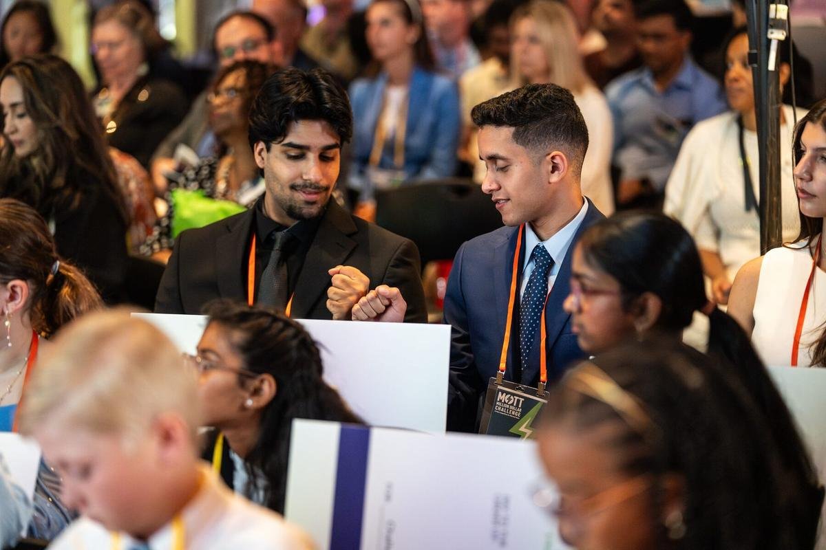 The two founders bump fists beside their prize cheque at the national finals